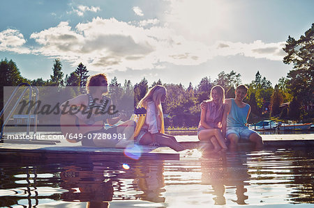 Two young couples relaxing on pier, Gavle, Sweden