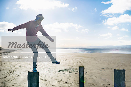 Young man standing on groynes, Brean Sands, Somerset, England