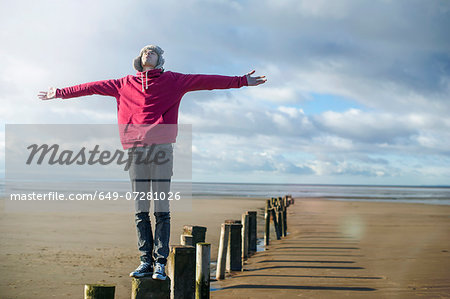 Young man standing on groynes, Brean Sands, Somerset, England