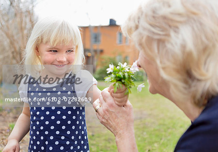 Girl giving grandmother flowers to smell