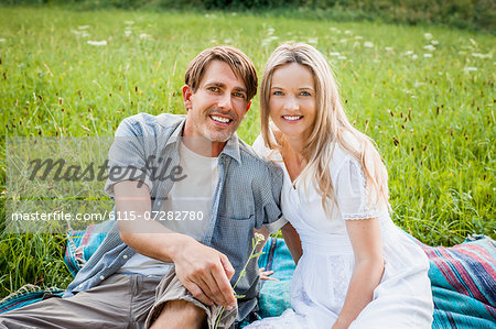 Happy couple sits in the meadow, foothills of the Alps, Bavaria, Germany