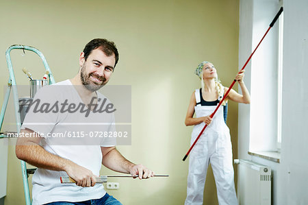 Woman painting the walls, man sits in the foreground, Munich, Bavaria, Germany