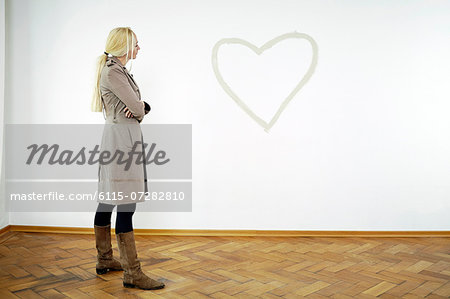 Young woman looking at heart shape on wall, Munich, Bavaria, Germany
