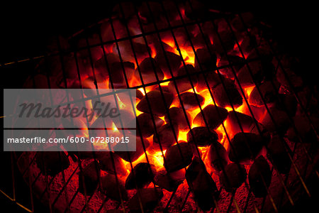 Close-up of hot charcoals glowing from underneath barbeque grill, Germany