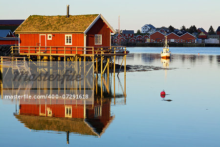 Traditional red rorbu hut with sod roof in town of Reine on Lofoten islands in Norway during polar day