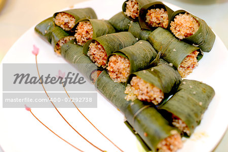 Sticky rice wrapped and steamed in bamboo leaves on a white plate