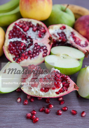 Fresh pomegranate and apples on a wooden table, selective focus
