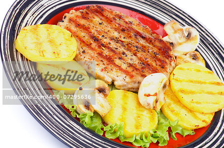 Roasted Turkey Steak Garnished with Grilled Sliced Potato, Portabello Mushrooms and Lettuce closeup on Striped Plate