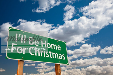 I'll Be Home For Christmas Green Road Sign Over Dramatic Clouds and Sky.