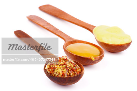 Arrangement of Various Mustards with Whole Grain, Dijon and Honey in Wooden Spoons isolated on white background