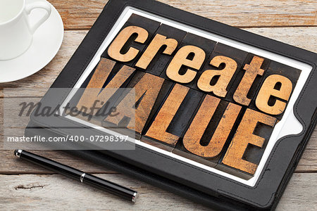 create value - inspirational text in vintage letterpress wood type on a digital tablet with a cup of coffee