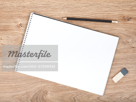 Blank notepad, pencil and eraser on the wooden table. View from above