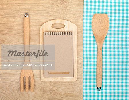 Kitchen utensils with notepad for copy space on wooden table