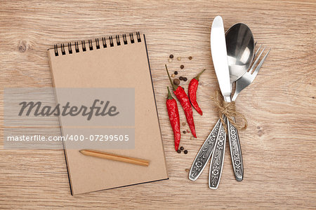 Blank notepad with pencil and silverware set on wooden table