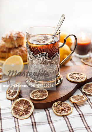 Black tea with lemon in the silver glass-holder with dry lemon around