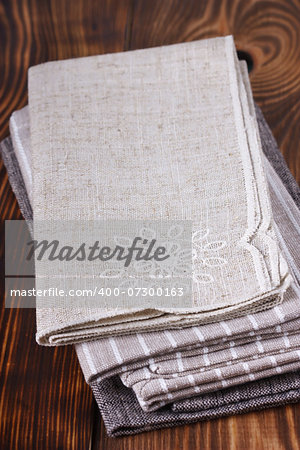Pile of linen table napkins on a wooden background.