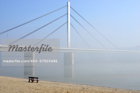 Winter day on Danube river with bridge in fog
