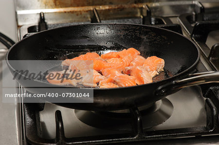 pieces of red fish frying on oil in the pan