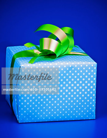 Gift Box with White Polka Dot, Green Ribbon and Bow isolated on Blue background