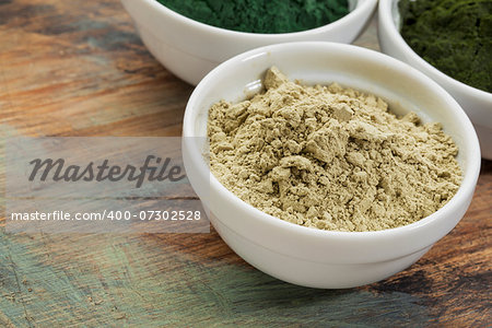 a bowl of kelp seaweed powder with spirulina and chlorella in background