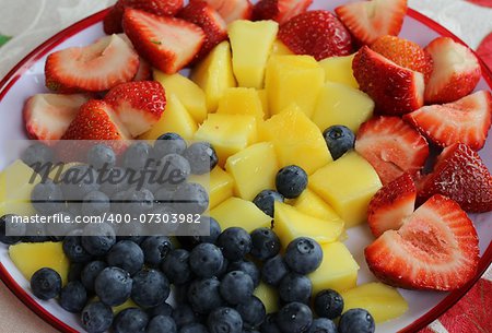 Plate of fruit salad with blueberry, strawberry and mango