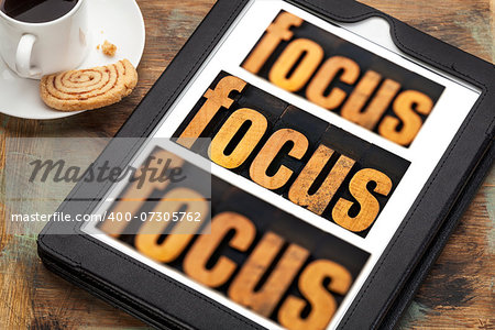 focus word in and out of focus  - text in vintage letterpress wood type on a digital tablet with a cup of coffee