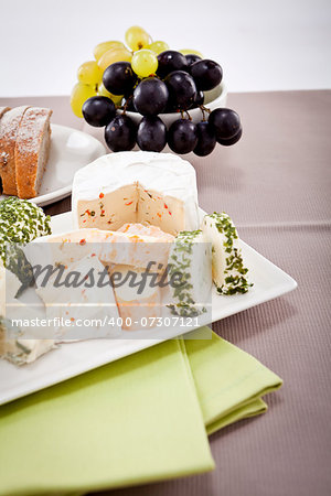 different cheese types on plate with grapes and red wine on wooden table