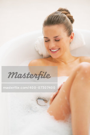 Smiling young woman laying in bathtub