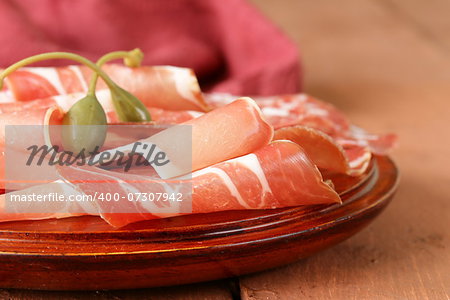 sliced ??dried sausage meat (ham, prosciutto, salami) served on a wooden board