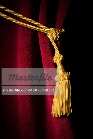 Red velvet curtain with tassel. Close up black isolated curtain