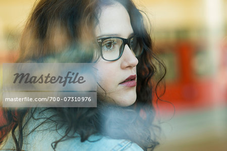 Close-up portrait of teenage girl wearing eyeglasses and looking out window, Germany