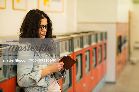 Teenage girl standing next to dryers in laundromat, using smart phone, Germany