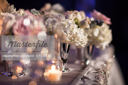 Close-up of flower arrangements in vases with candlelight on table at reception, Canada