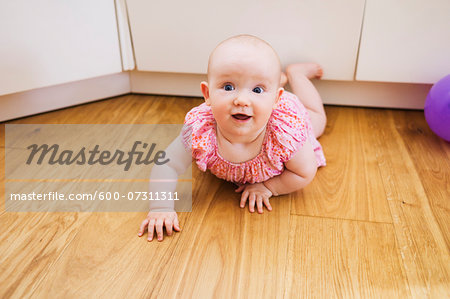 Portrait of Baby Girl lying on floor and Smiling at the Camera