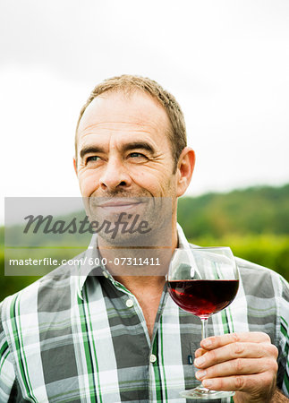 Portrait of vintner standing in vineyard, holding glass of wine, Rhineland-Palatinate, Germany Portrait of vintner standing in vineyard, holding glass of wine, Rhineland-Palatinate, Germany