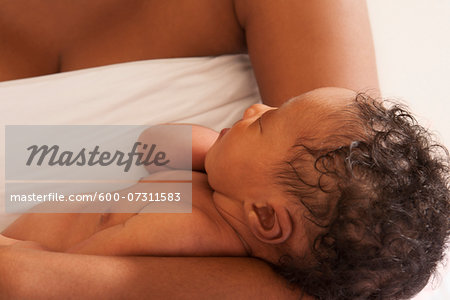 Sleeping Newborn Baby Cradled in Mother's Arms