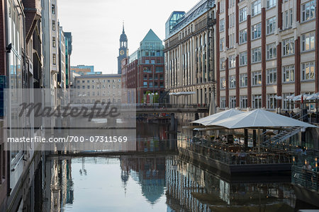 Canal with reflections of buildings on the water with a restaurant and umbrellas, in daylight, Hamburg, North Germany, Europe