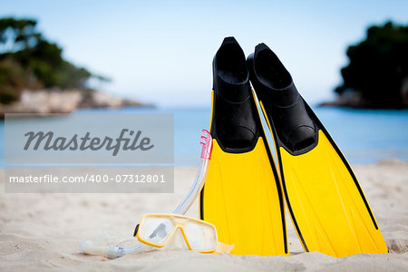 yellow fins and snorkelling mask on beach in summer holiday