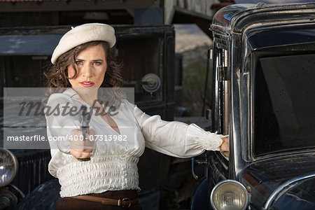 Retro 1920s era female gangster aiming gun next to car