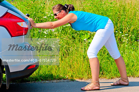 woman pushing car out of gasoline