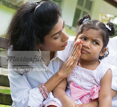 Indian family outdoor. Parent is comforting her crying child.