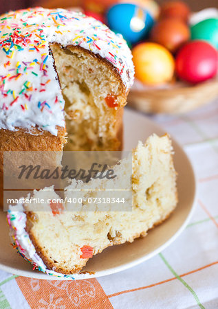 Piece of Easter cake with colored eggs on the background