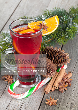 Christmas mulled wine with spices and snowy fir tree on wooden table