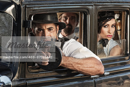 Armed gangster firing submachine gun from vintage automobile