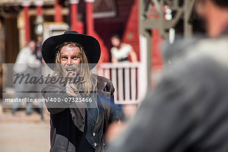 Cowboy Points Gun at Man in the Middle of Town