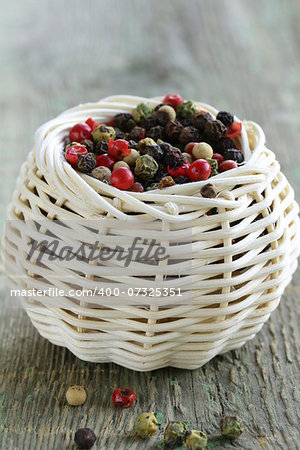 colorful peppercorn in wicker bowl on wooden table