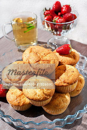 Fresh homemade muffins with tea and strawberry on the background