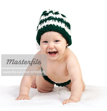Happy baby boy in knitted hat crawling over white