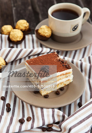 Portion of delicious tiramisu cake and coffee cup on the background