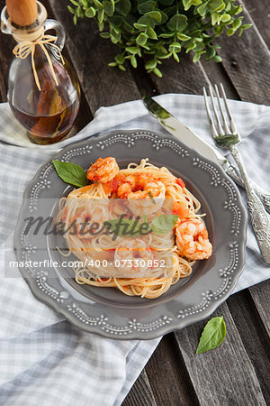 Plate of fresh spaghetti with prawns and tomatoes on wooden table
